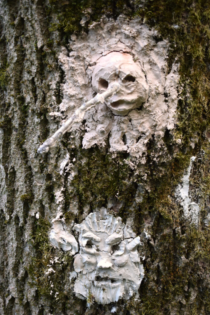 visages sculptés en argile, sur le tronc d'un arbre